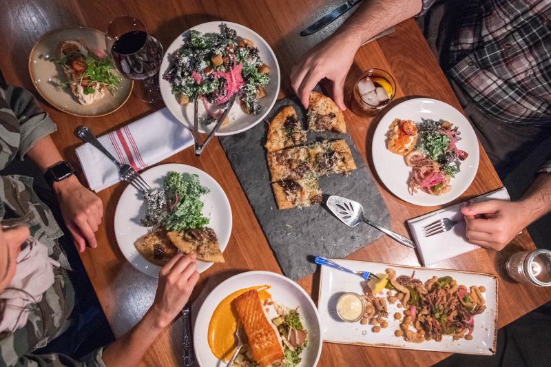 Table of salad, pizza, and more being shared between two people