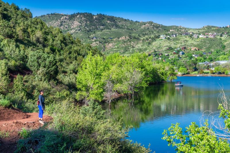 Hiker taking a break on the Bay-to-Bay Trail to admire the view of the reservoir and outdoors.