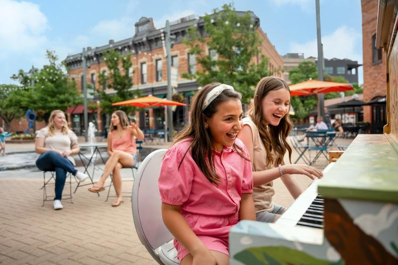 Two kids laugh and play piano at Old Town Square