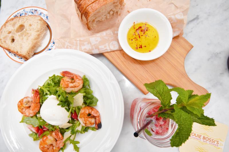 A plated shrimp salad and bread with drink at Louie Bossi in Fort Lauderdale, FL