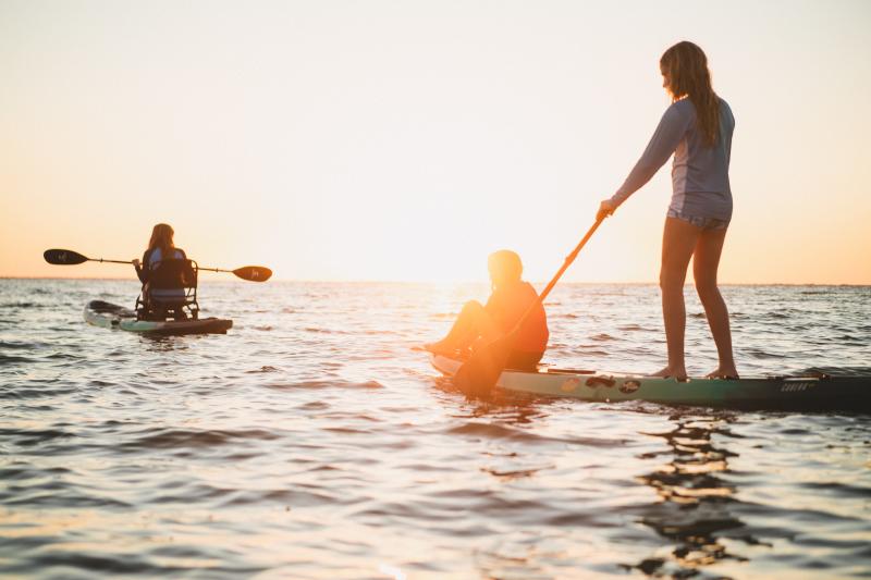 teens paddleboarding on st. joseph bay at sunset