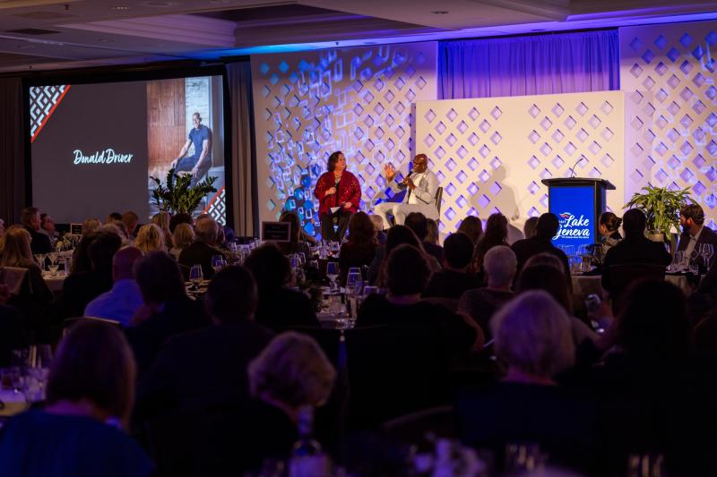 Donald Driver and Stephanie Klett talking on stage at the 2025 Annual Dinner and Impact Awards