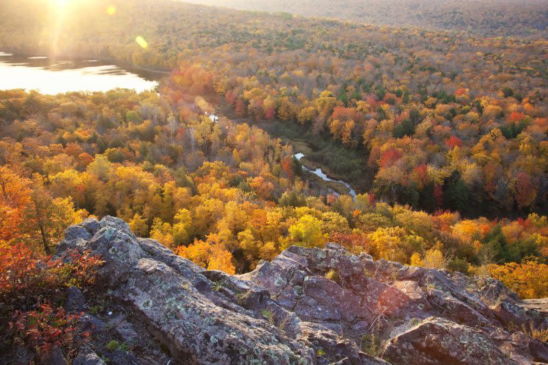 Autumn trees in full color with rocky cliff edge at Lake of the Clouds Michigan. Taken at sunrise.