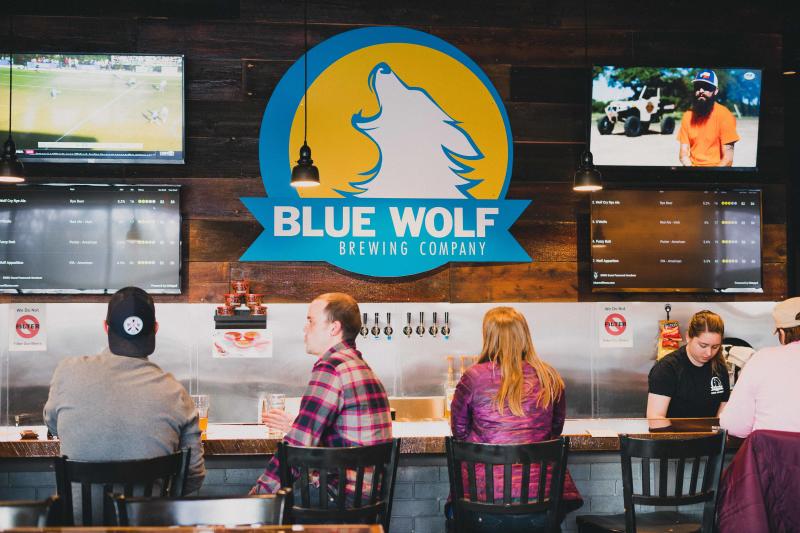 Patrons seated at the bar inside of the Blue Wolf Brewing Co