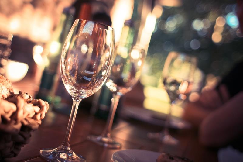 Two Wine Glasses sit on a bar with an out-of-focus background