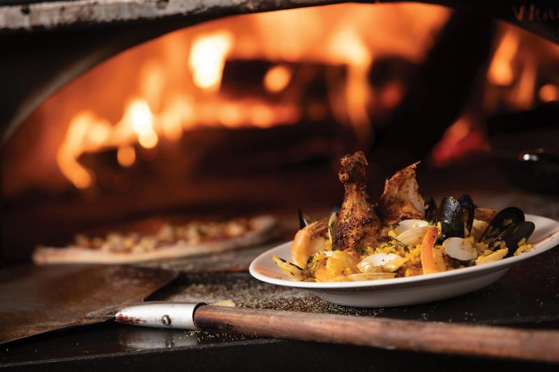 Kaiser Grill Paella dish in front of a pizza oven with fire