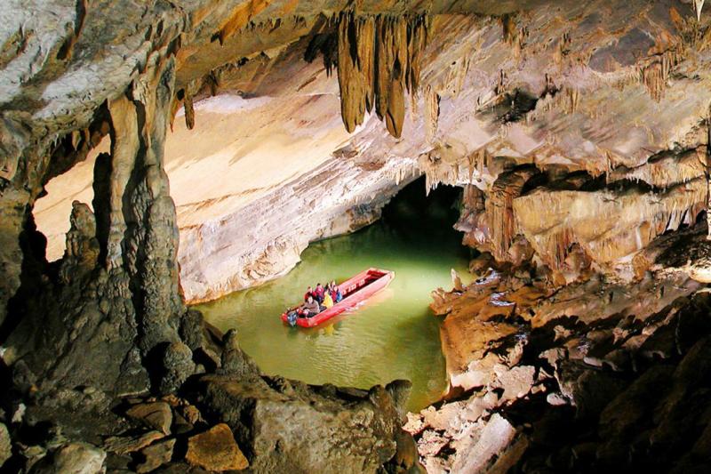 Boat filled with people moving through an eerie cave