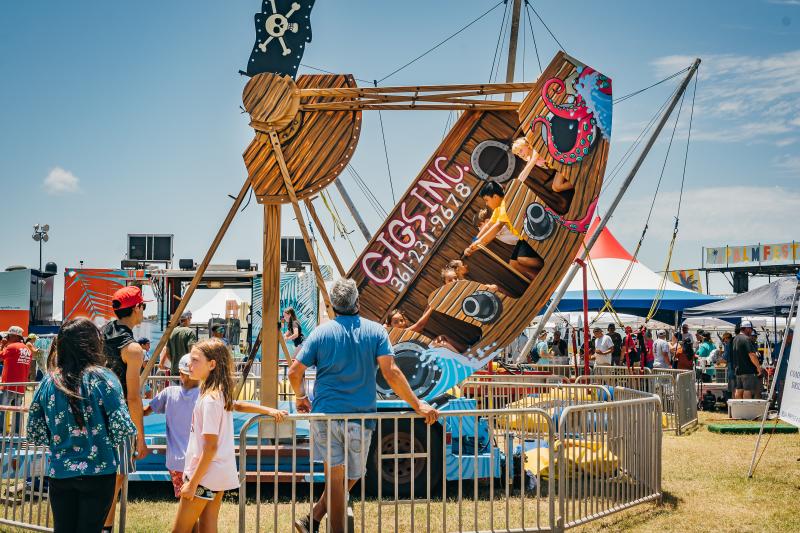 A kids' carnival swing ride in the shape of a pirate boat swings up to the right.