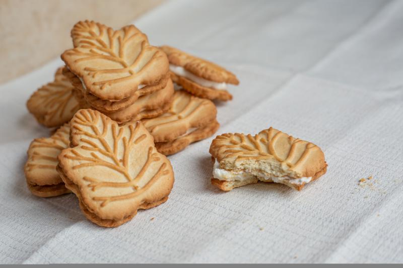 Maple cookies in the shape of a maple leaf. One with a bite taken out of it.