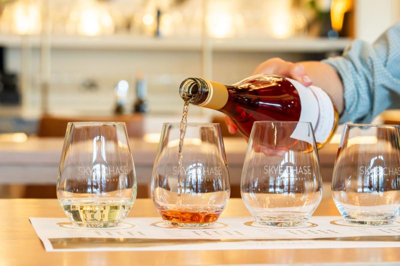 A bottle of rosé wine is poured into Skye Chase Estate Winery tasting glasses during a wine flight.