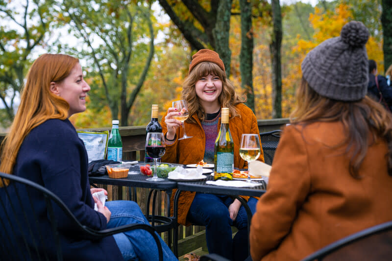 Friends enjoying wine outside on a patio in Historic Missouri Wine Country in the fall.