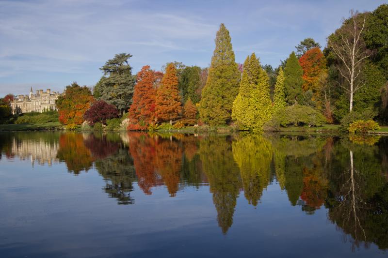 Sheffield Park house in distance with autumnal trees alongside the lake