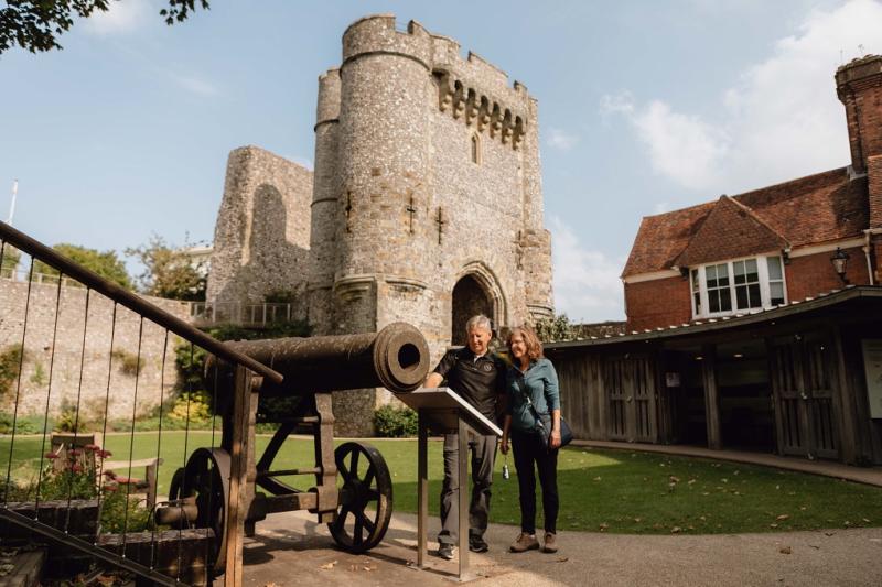 lewes castle tower in background with a couple looking an information board in front