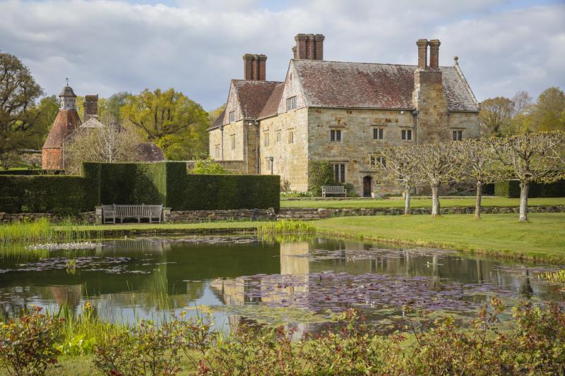 Batemans jacobean house with topiary and pond in foreground