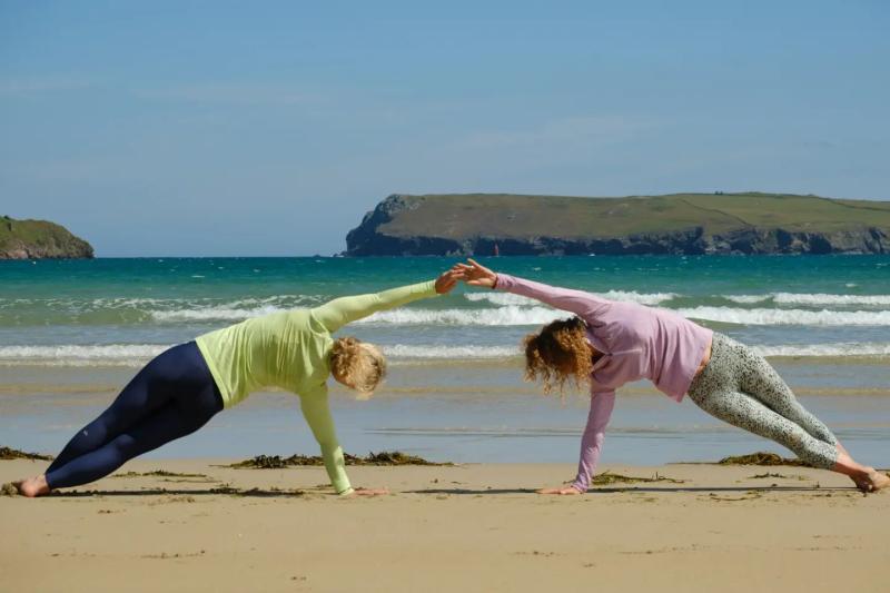Two people doing yoga on the sandy beach at the Witterings