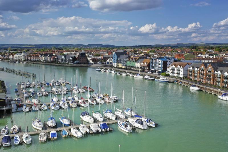 Yachts moored on the river at Littlehampton harbour, with riverside apartments on the opposite side