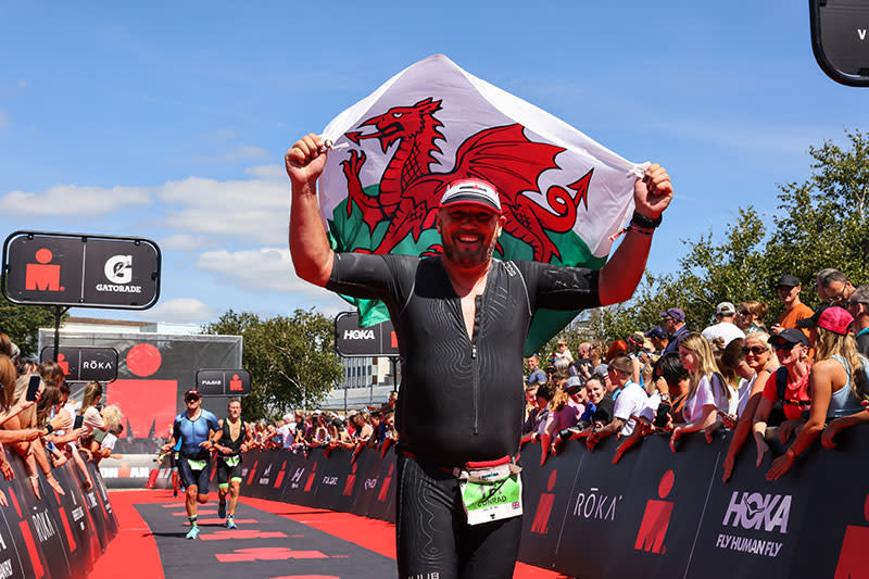 An Ironman competitor holding a Welsh flag aloft.