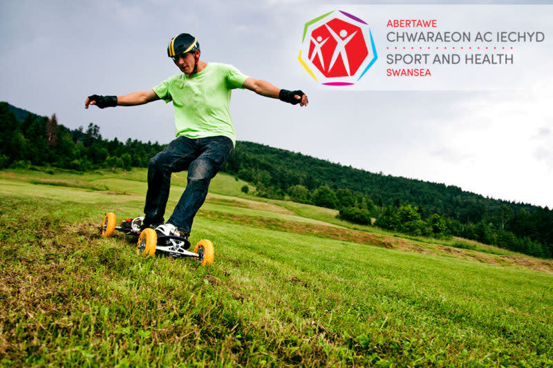 A man on a mountain board in a field.