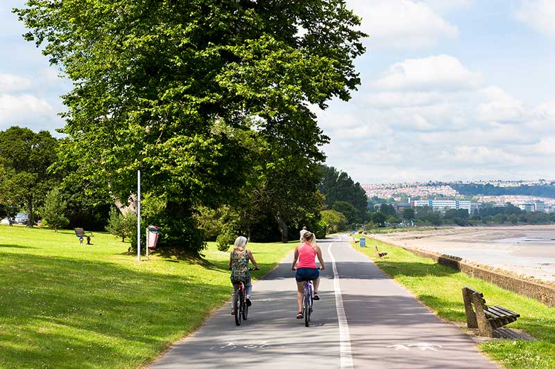 Two women cycling along the bike path on Swansea prom.