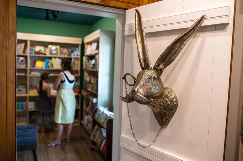 Looking into the children's room of a bookstore, past a bronze rabbit wearing a monocle