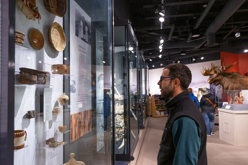 a man looks at a museum display of Alaska Native artifacts