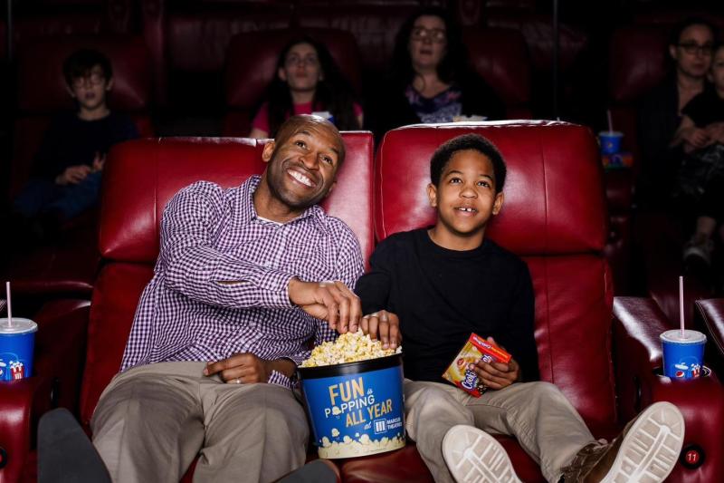 Father and son share popcorn while watching a movie at the Movie Tavern in Collegeville