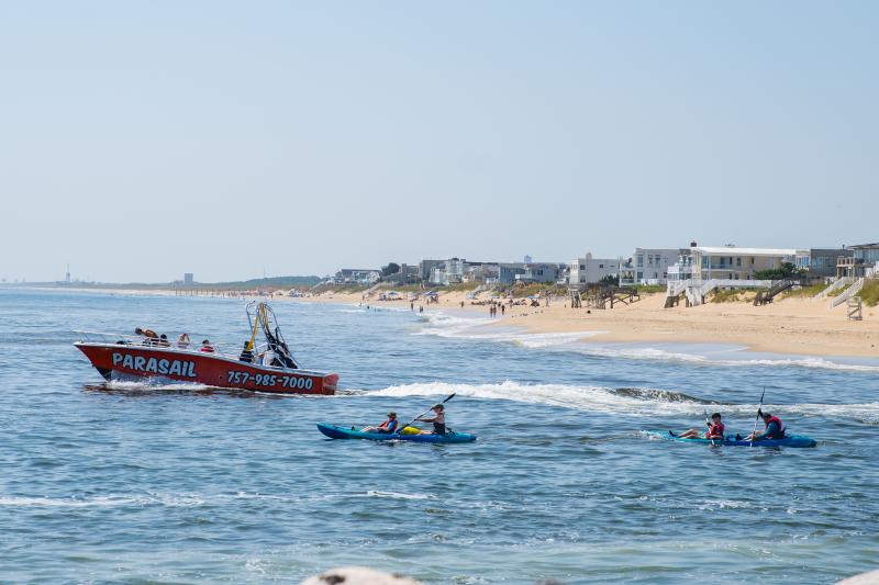 two kayaks and a larger boat in the ocean near the coast