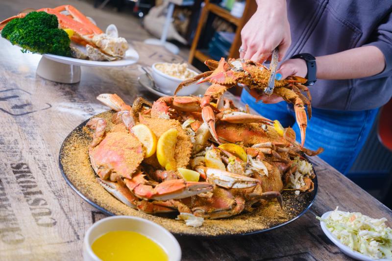 Person cracking into a blue crab feast