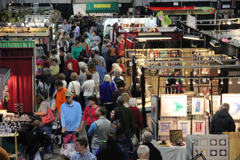 crowd of people moving along booths at a craft fair