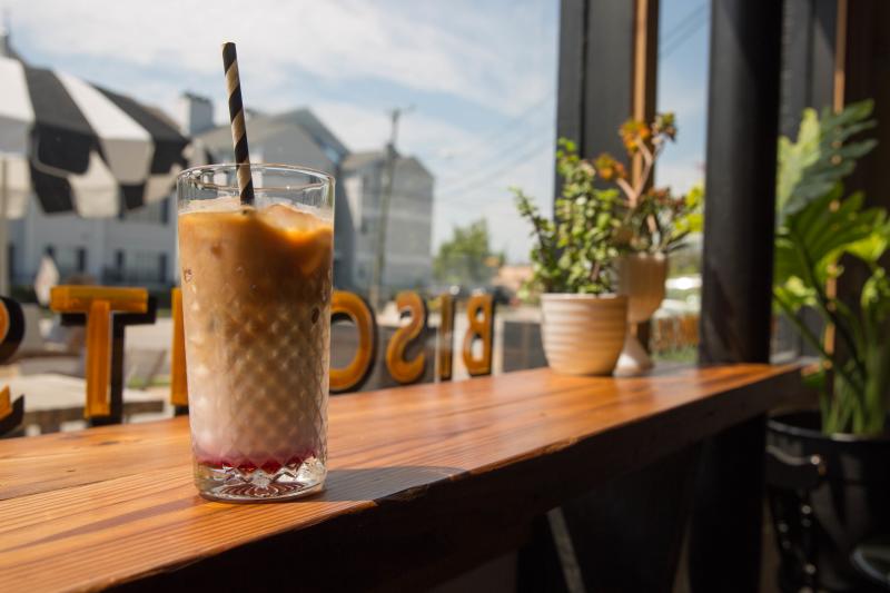 iced coffee glass with striped paper straw sitting on high top bar overlooking window