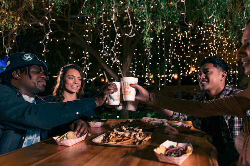 friends cheersing drinks at an outdoor bar