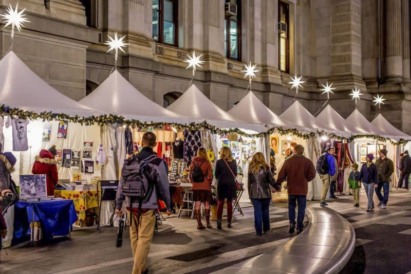 People shop at vendor tents at an ourdoor holiday market