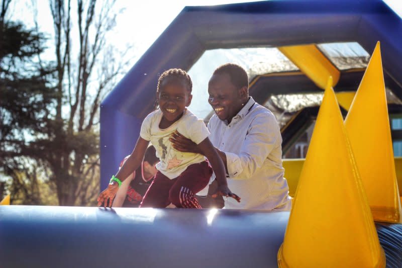 a man holds onto a young boy while enjoying an inflatable at a Tuff Nutterz event.