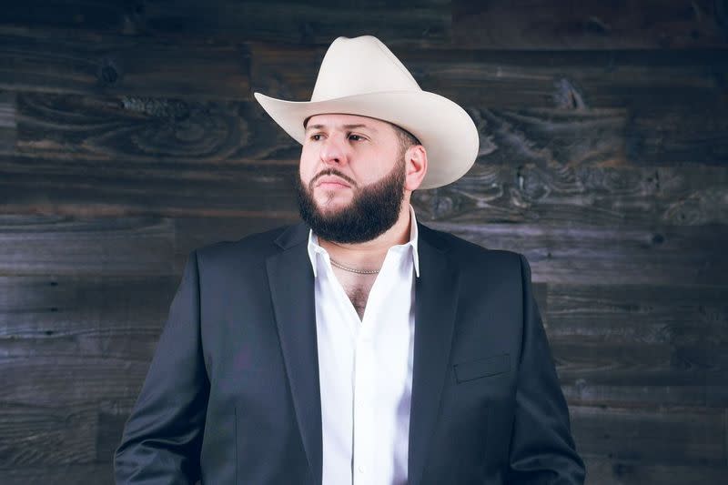 El Fantasma poses for a photo wearing a white felt cowboy hat.