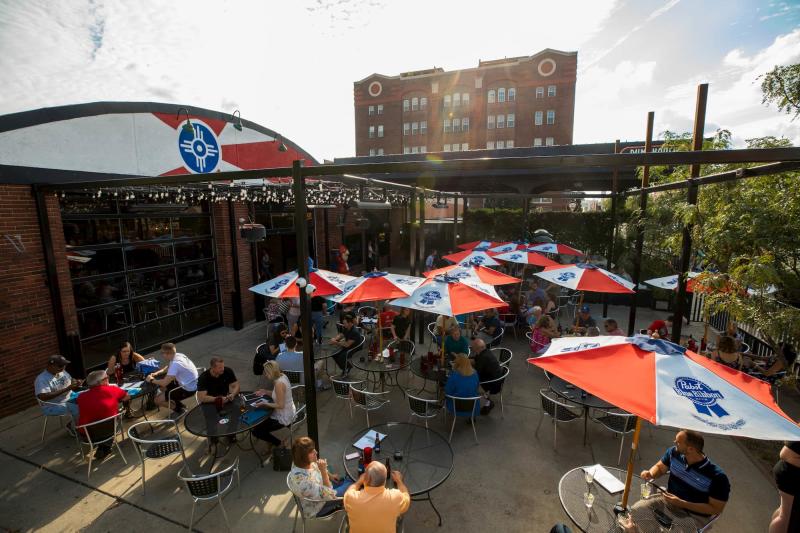 A sunny day greets a full patio of people eating and drinking at Pumphouse in Old Town