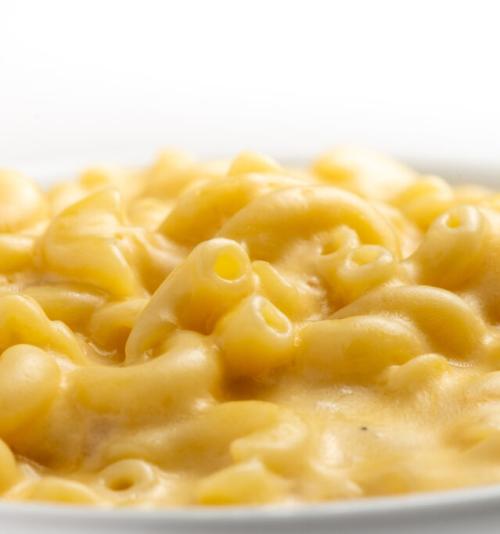 A close-up of creamy macaroni and cheese served on a white plate with a white background.