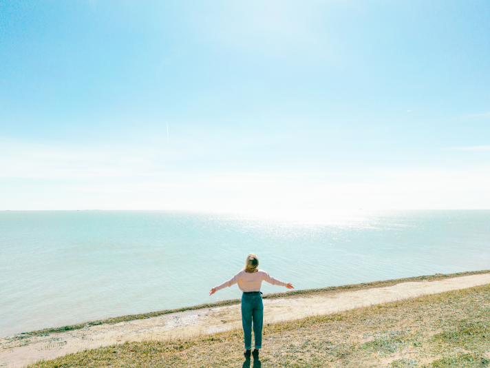 woman with arms out in front of water