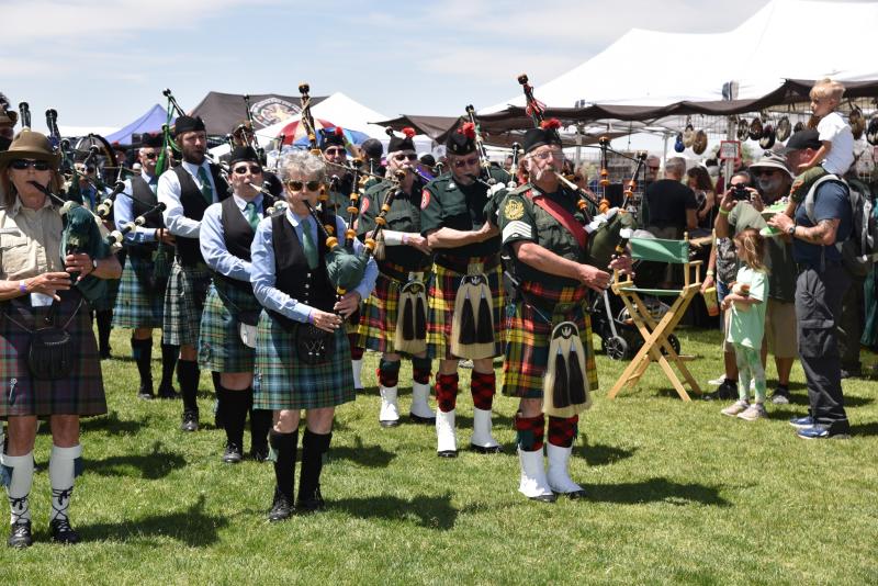 Bagpipe players play as a crowd of people watches