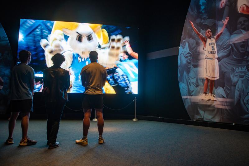 People watching a video at the Carolina Basketball Museum