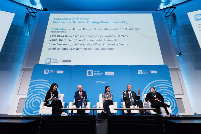 5 speakers sit on a stage a conference