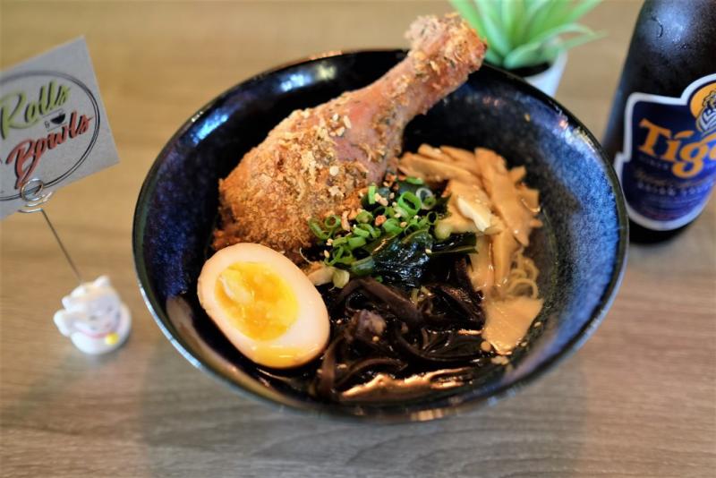 Chicken leg in a bowl with rice noodles and an egg from Rolls & Bowls