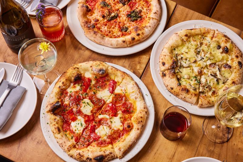 Different style of pizzas served with wine at ACRE kitchen and bar in Oakland California