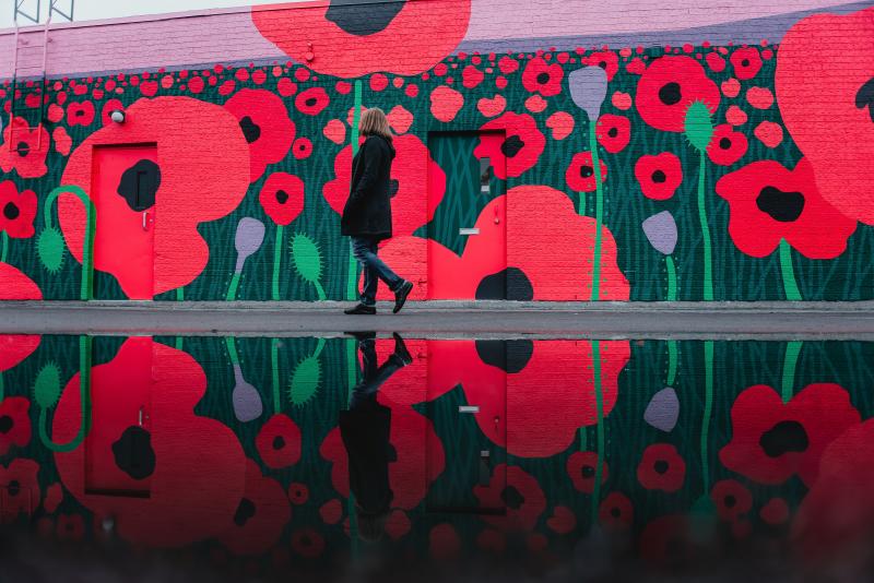 woman walking in front of mural