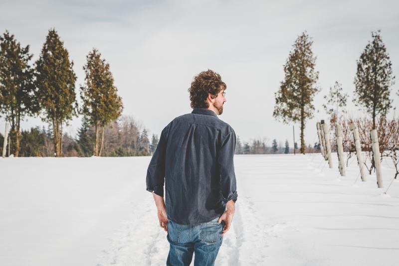 Man walking snowy vineyard