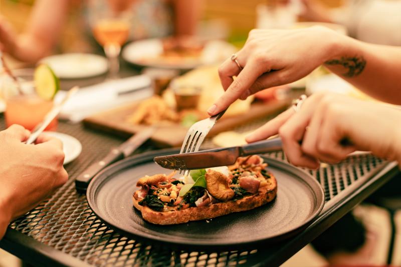 Person cutting into a dish at an outdoor table at Esoteric in Virginia Beach