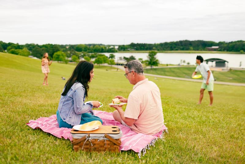 Couple having picnic with kids playing in background