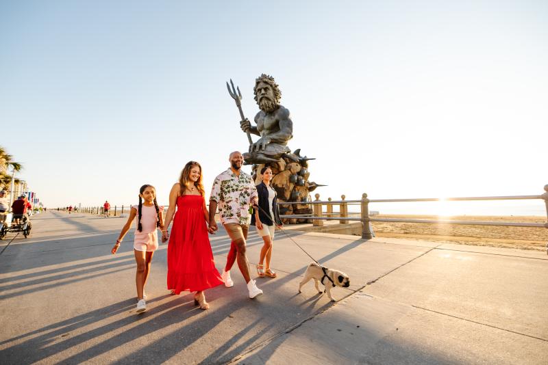 family walking on beachfront boardwalk with dog