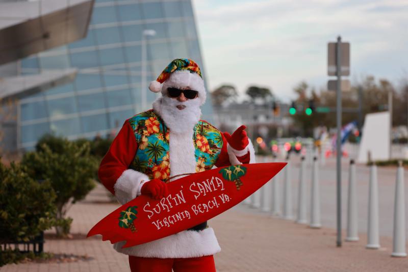 person dressed as Santa Claus holding surfboard