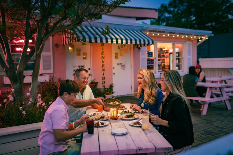 family dining at pink picnic table in front of pink restaurant at dusk