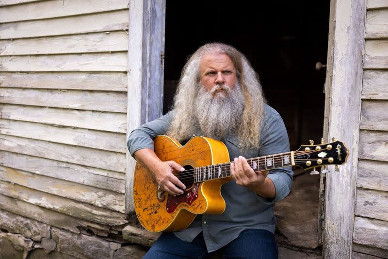 Artist Jamey Johnson poses for a photo holding a guitar.